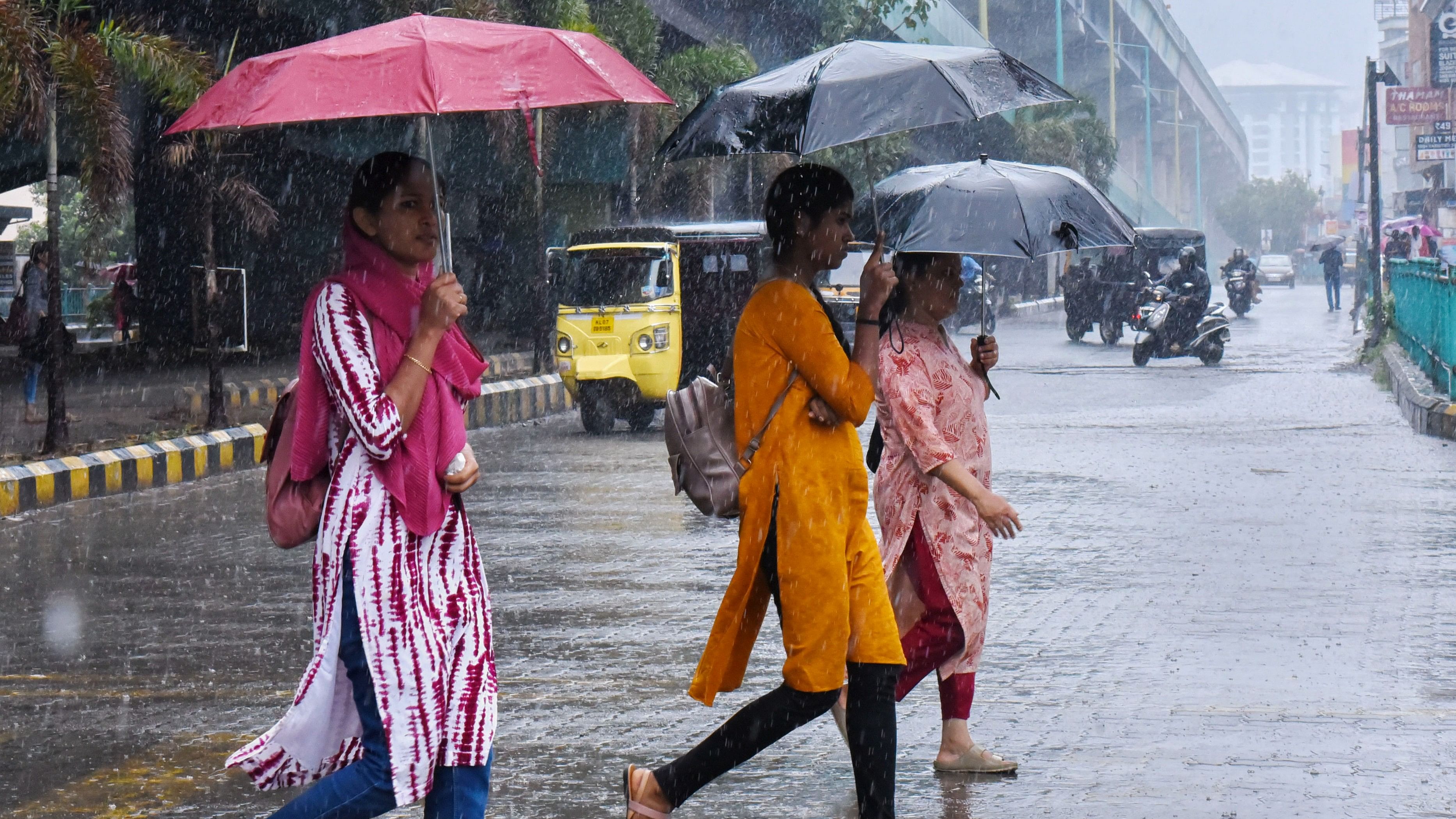 <div class="paragraphs"><p>Pedestrians cross a road amid rain, in Kochi</p></div>